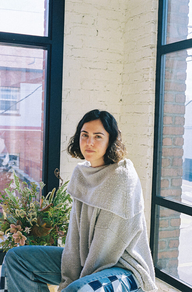 Film branding portrait of a Bay Area therapist beside flowers in a light-filled studio.