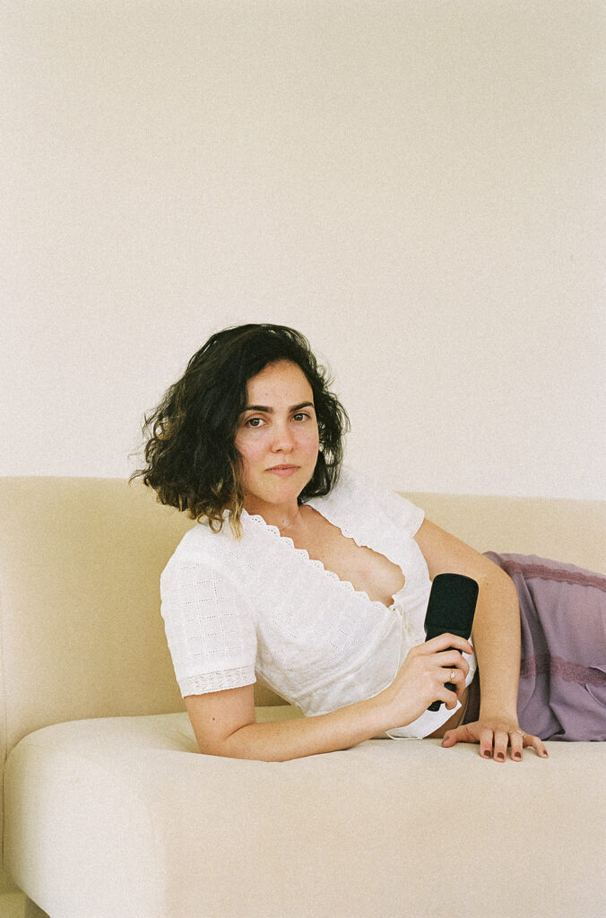 Bay Area therapist resting on a couch while holding a podcast microphone.