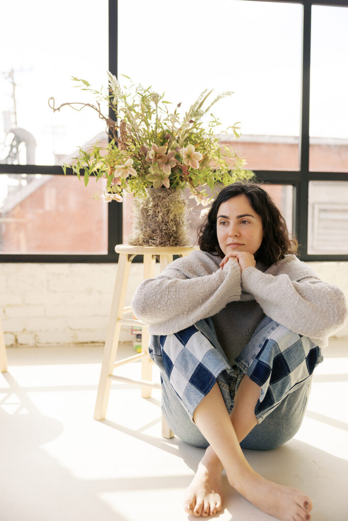 Therapist sitting on the floor of a light-filled Bay Area studio for her therapist brand photoshoot.
