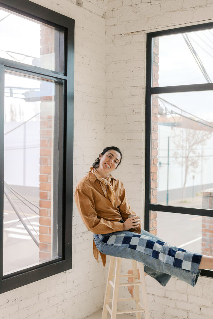 Bay Area therapist sitting by a window during an editorial branding photoshoot while making a silly face.