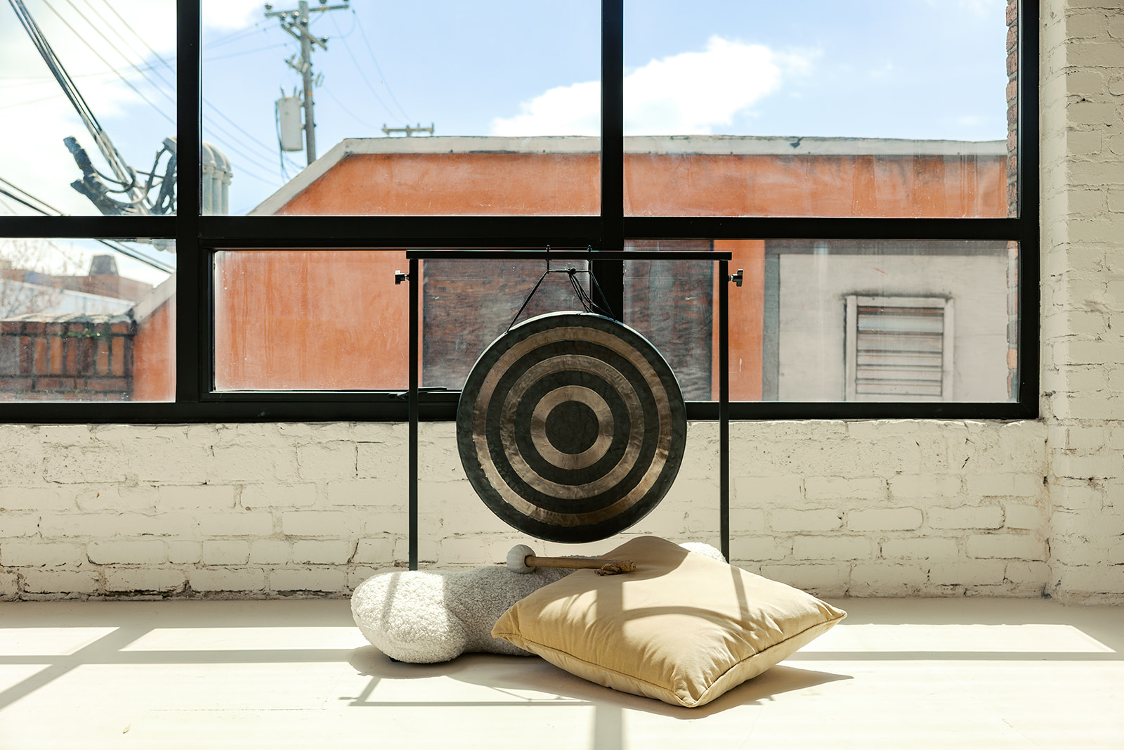 Gong and sound healing tools in a light-filled studio for a therapist branding session.