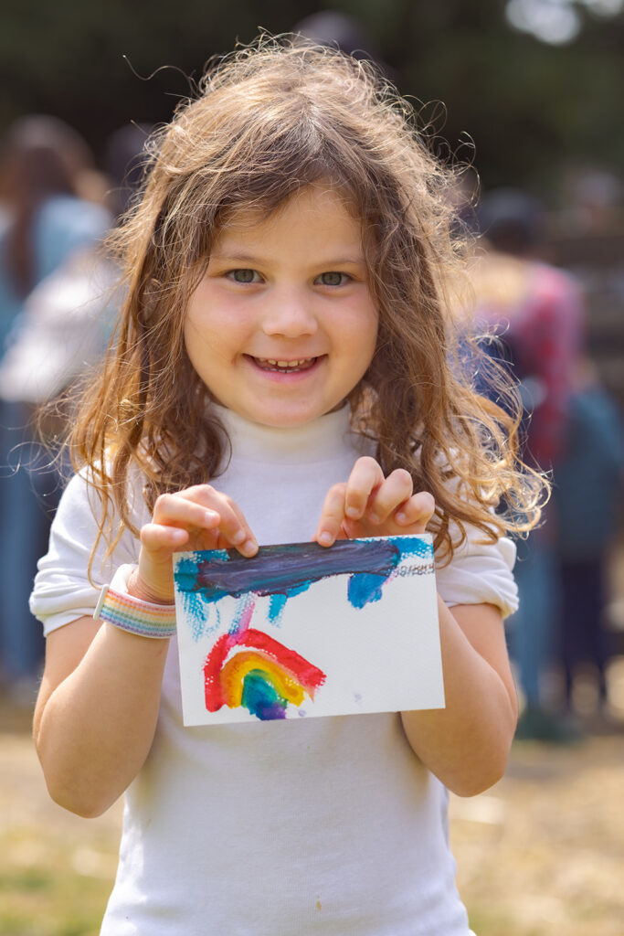 Little girl holding up a painting.
