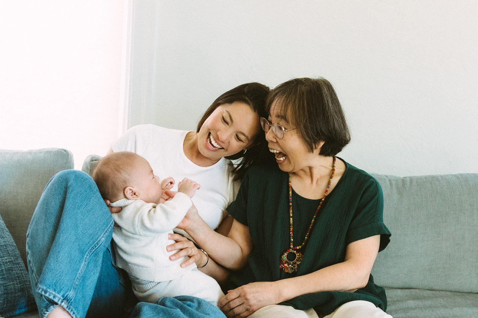 Mother, grandmother, and baby playing together during an at-home newborn photography session.