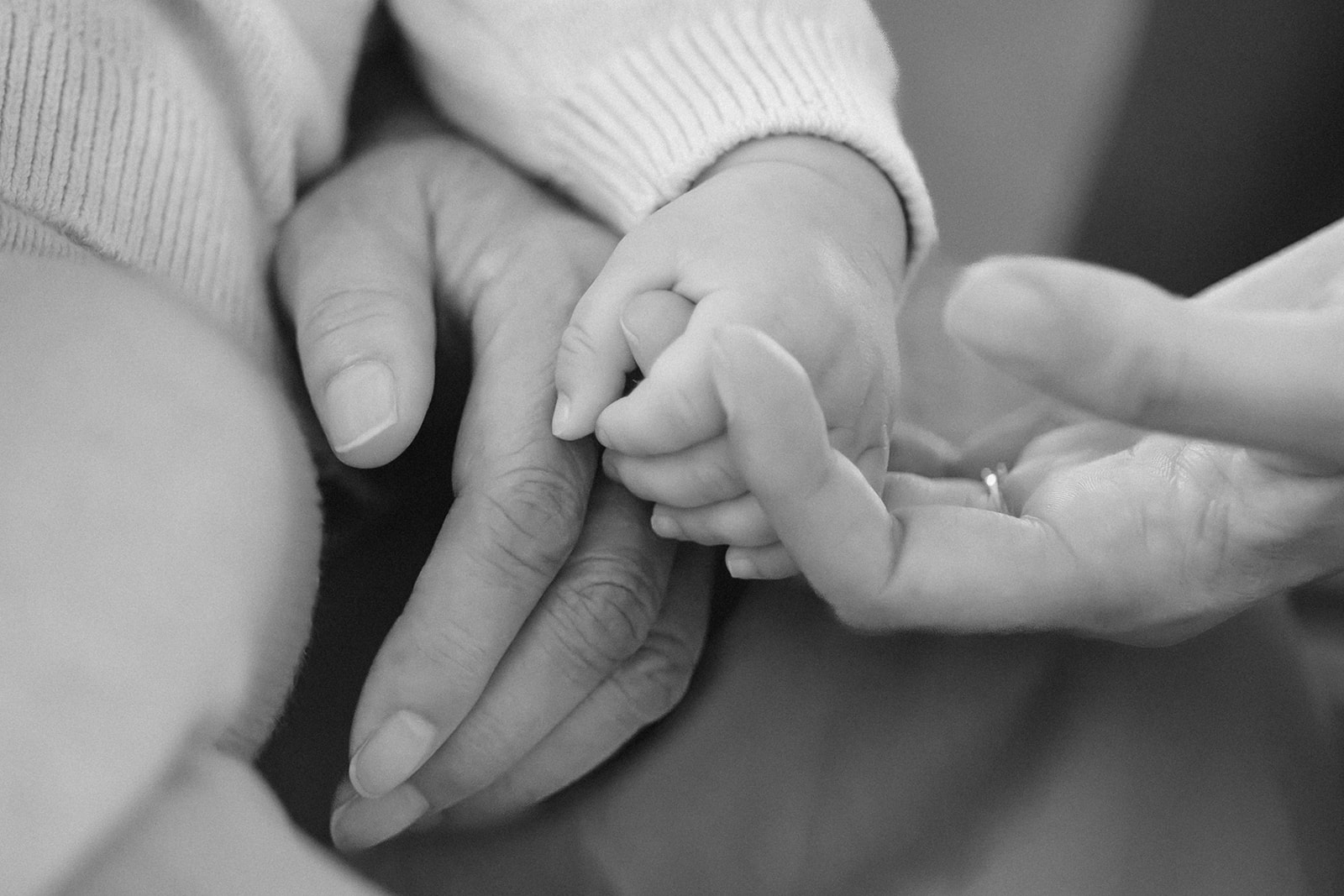 Black and white photo of a mother holding her babies hand.