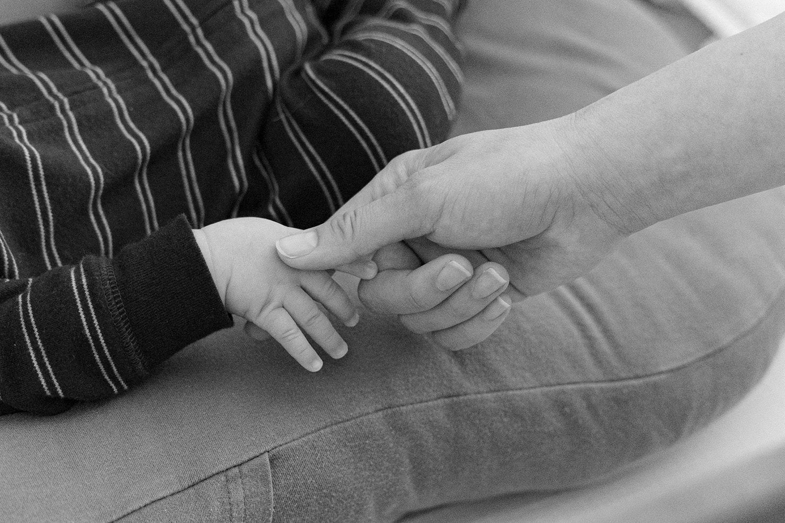 Black and white photo of a mother holding her baby's hand. 