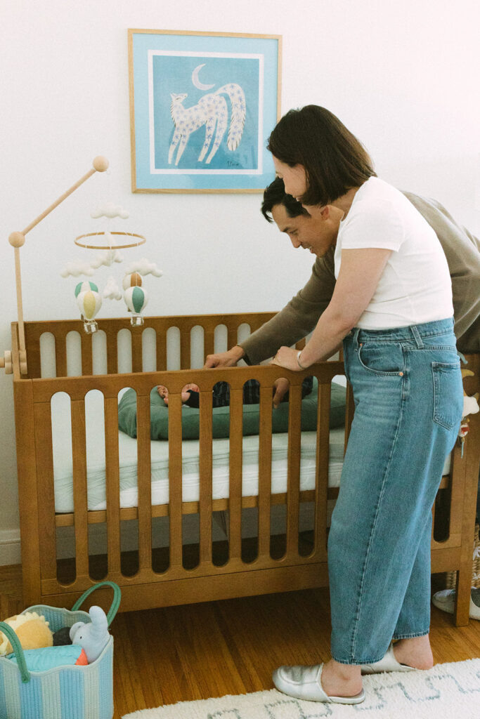 Parents interacting with their newborn as he lays in his crib during their at-home Bay Area newborn photography session.
