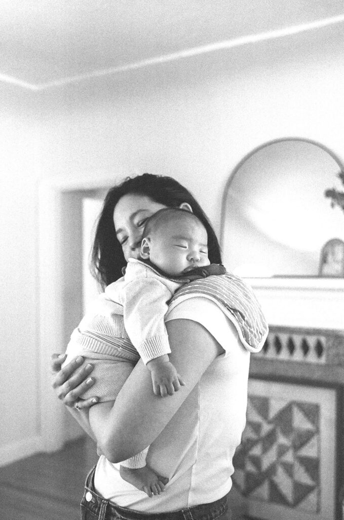Black and white film photo of a mother holding her newborn.
