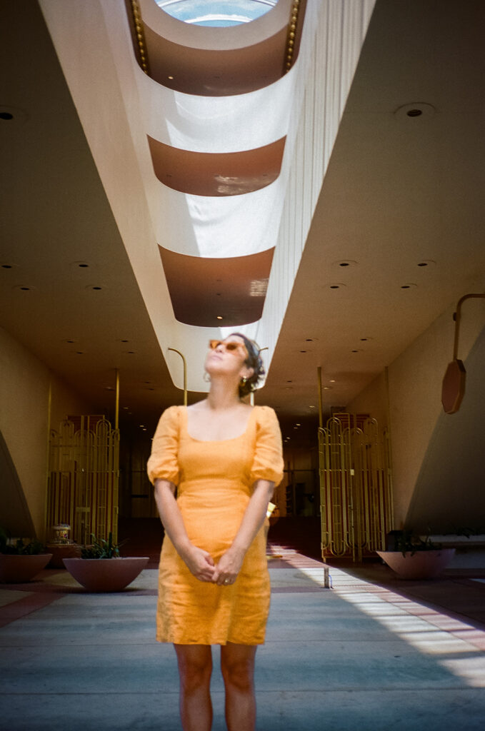 Creative 35mm film portrait of a woman standing under dramatic skylight at Marin County Civic Center.