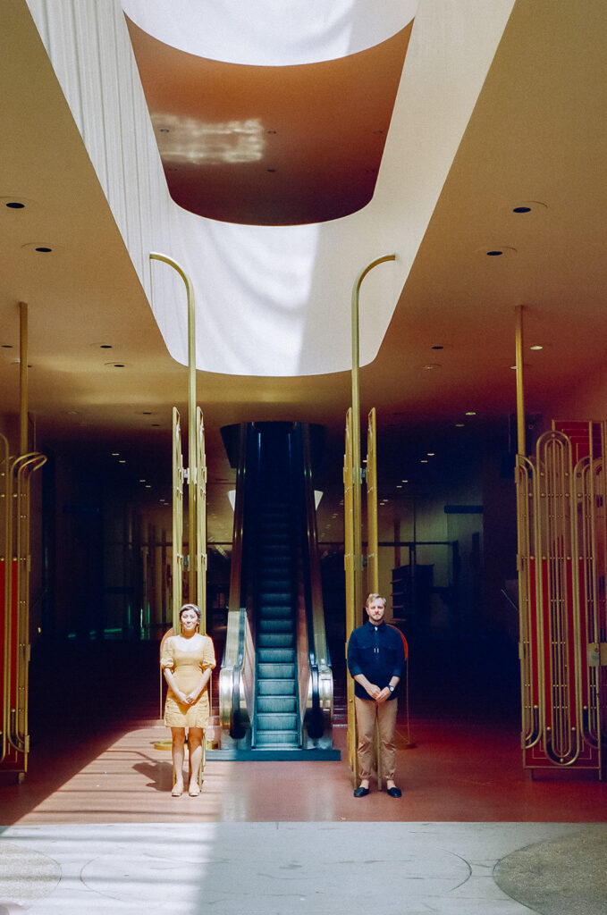 Bay Area engagement photos on film with a couple standing near escalators and dramatic light.