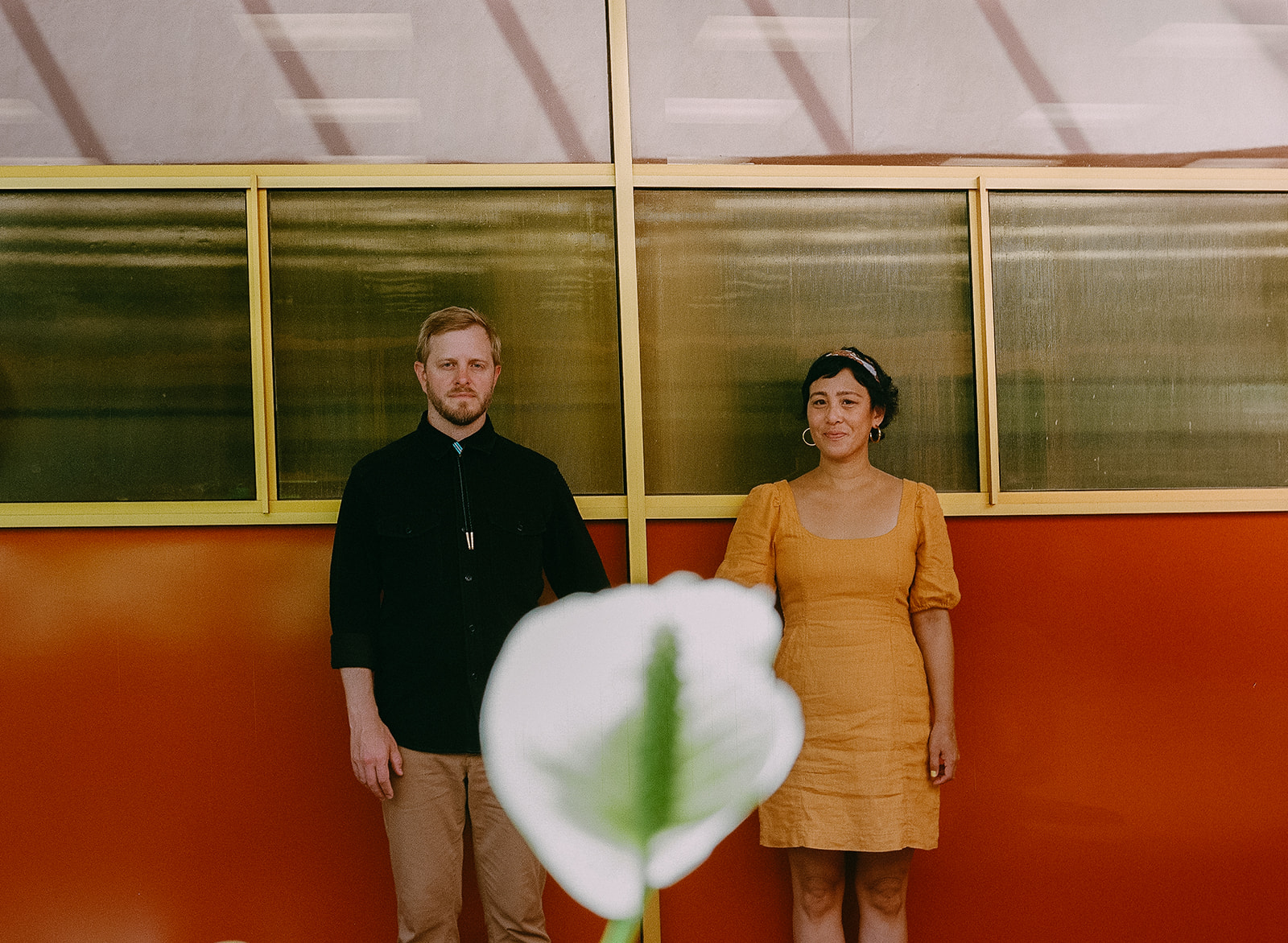 Bay Area engagement photos on film with a couple standing behind a white flower at Marin County Civic Center.
