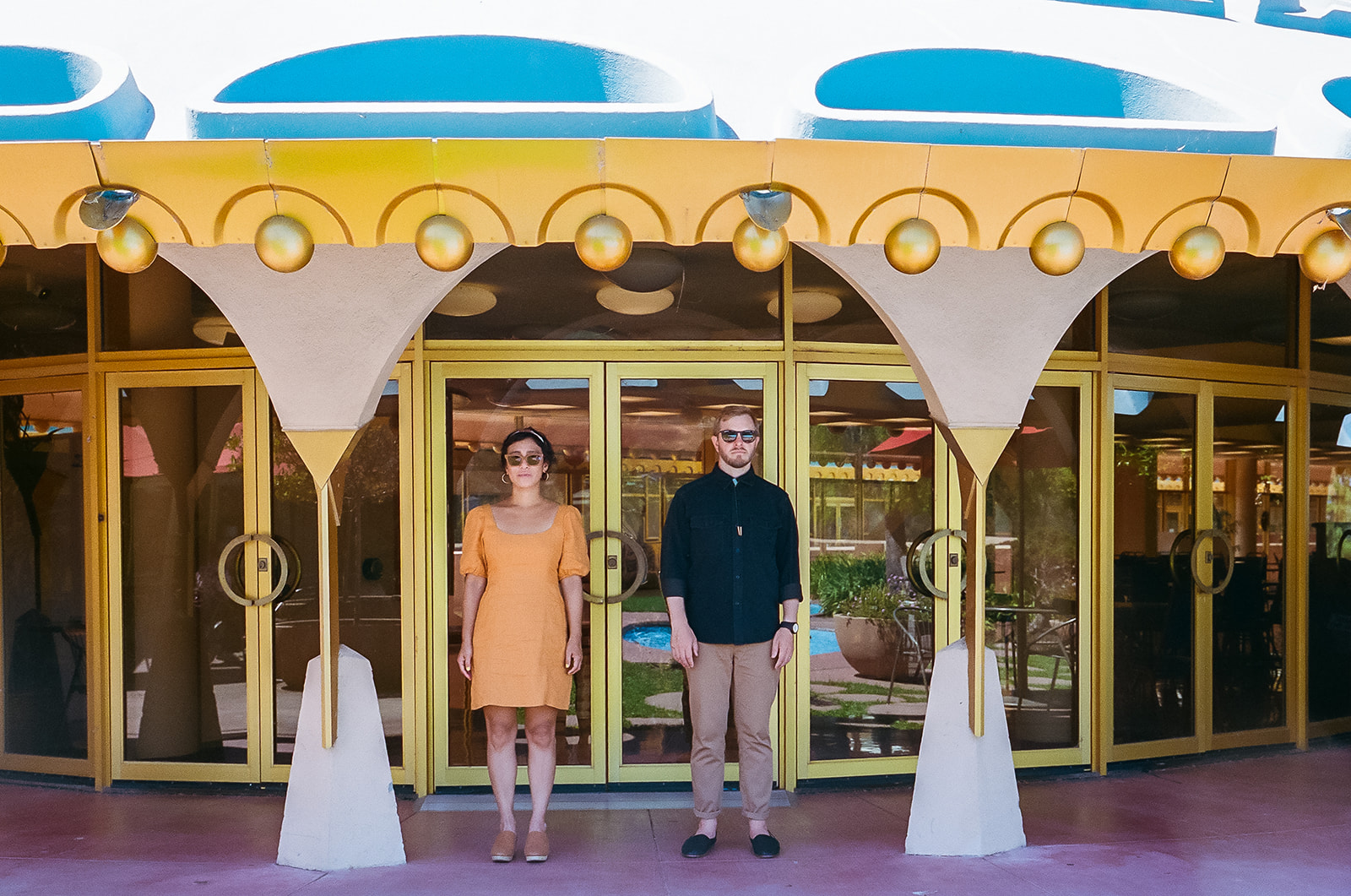 Bay Area engagement photos at Marin County Civic Center with a couple standing beneath colorful Frank Lloyd Wright architecture.