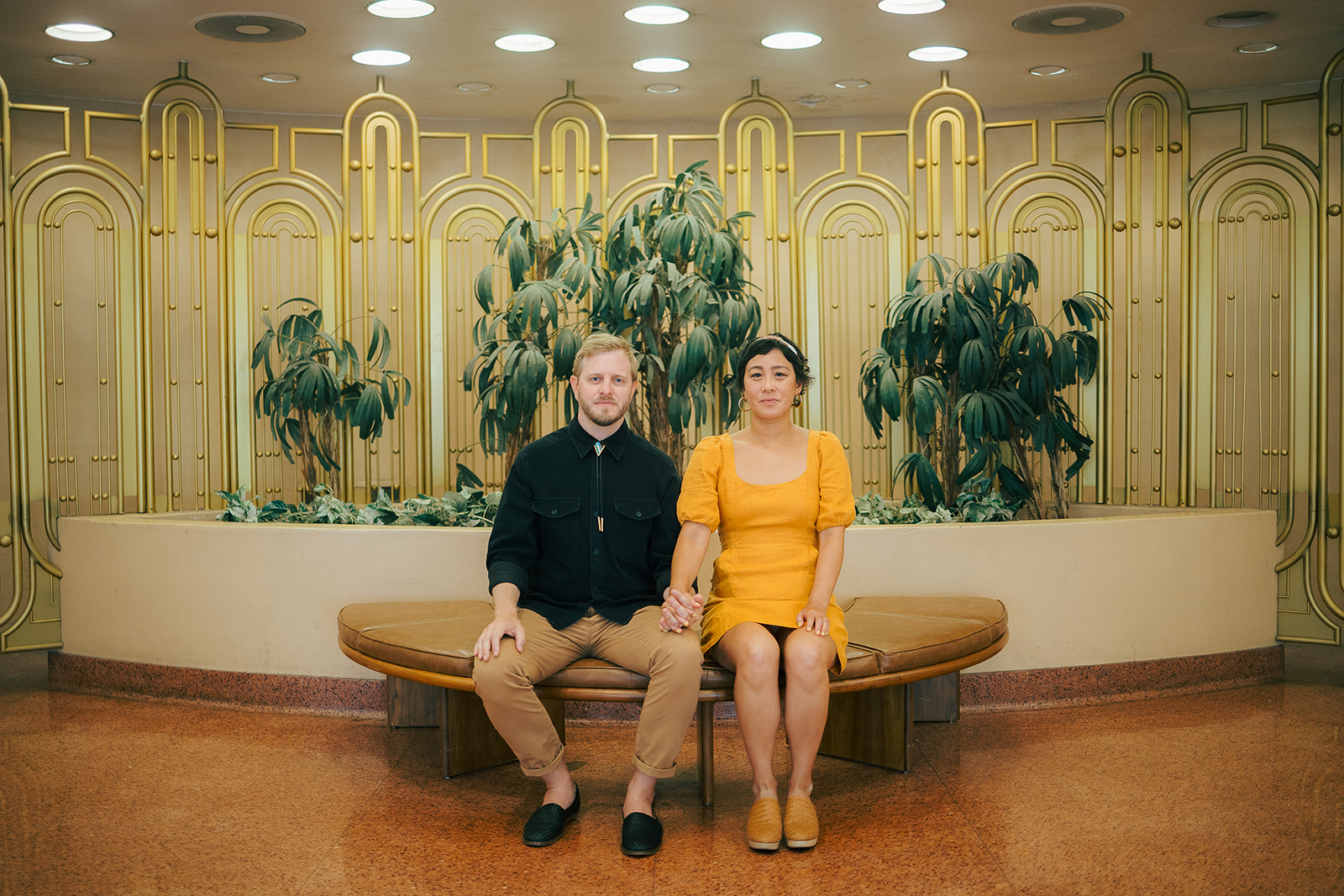 Bay Area engagement photos at Marin County Civic Center with a couple sitting in front of gold architectural details.