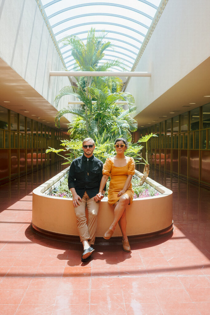 Couple sitting together inside Marin County Civic Center for colorful film-inspired Bay Area engagement photos.