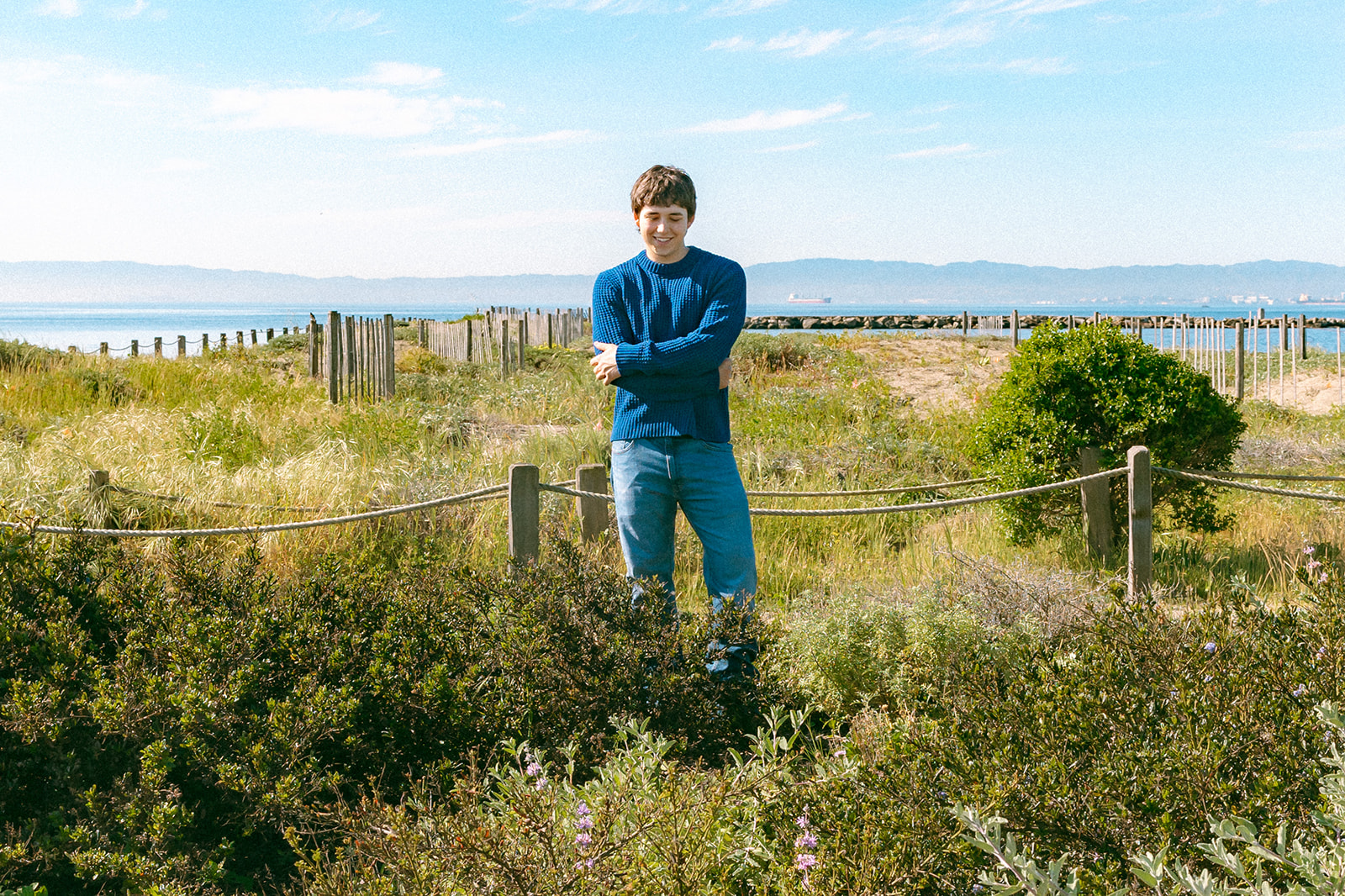 Candid senior portrait among greenery near the Alameda Rock Wall with the Bay in the background.