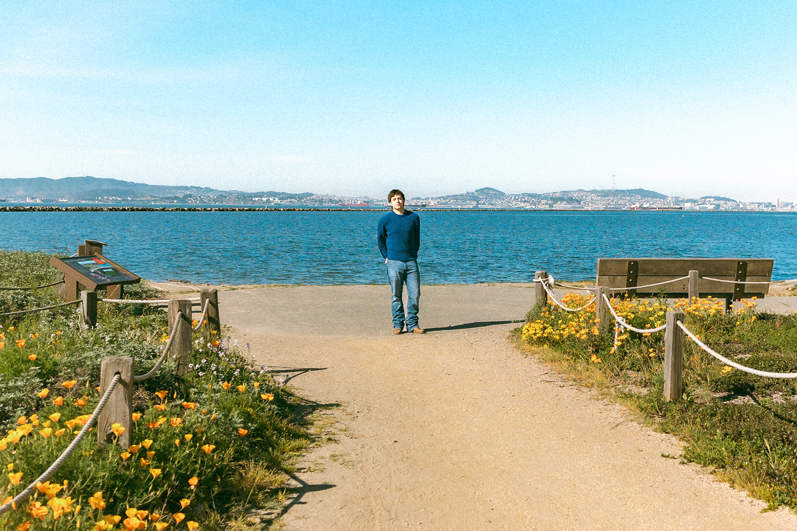 Film senior portrait by the Bay in Alameda with spring flowers and the East Bay hills in the distance.