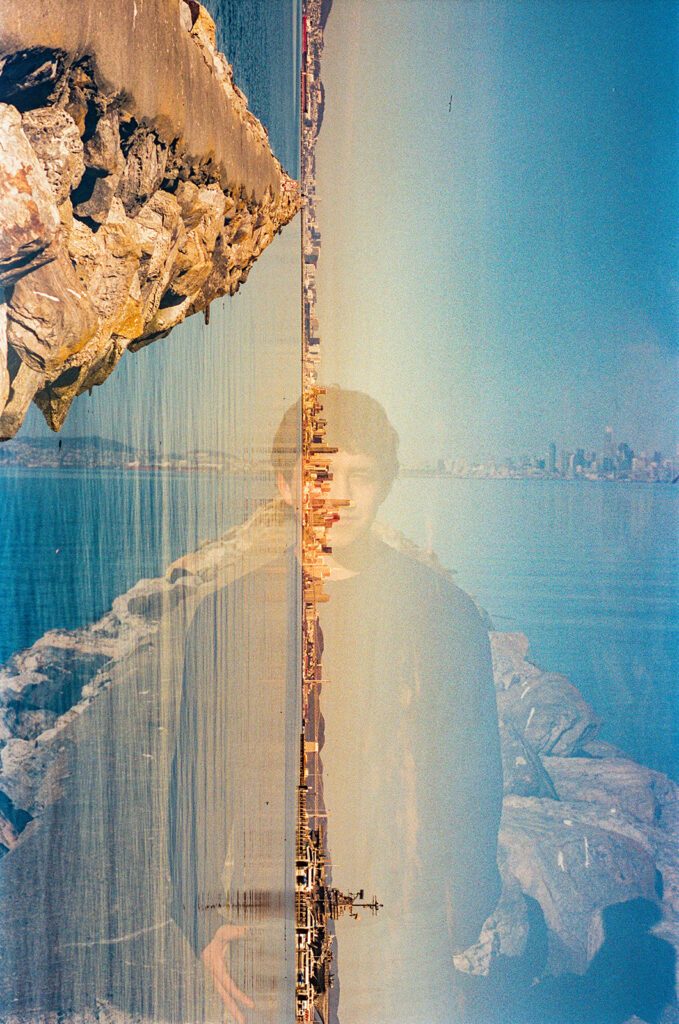 Creative double exposure film senior portrait blending the Alameda Rock Wall, Bay, and senior into one image.