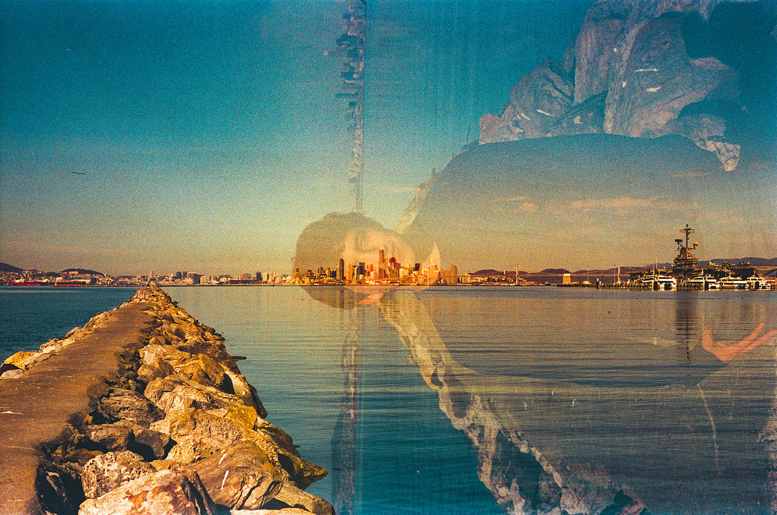 Double exposure film senior portrait blending the Alameda Rock Wall, San Francisco skyline, and senior into one creative image.