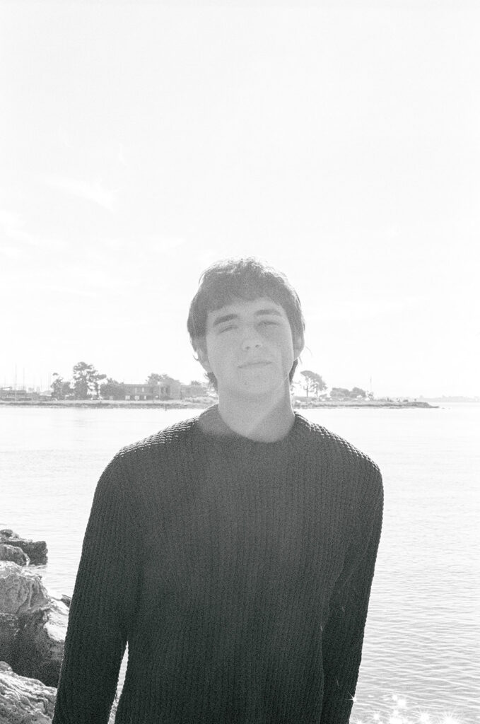 Black and white film close-up senior portrait beside the water at the Alameda Rock Wall.
