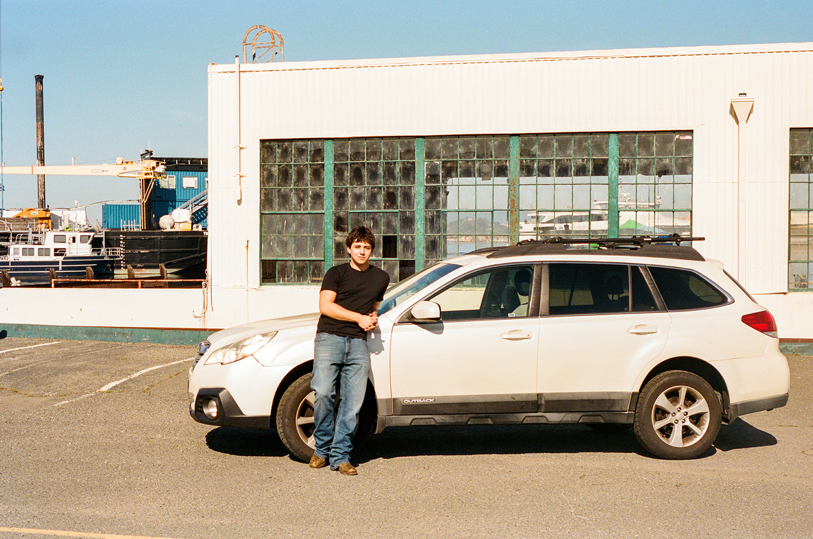Film senior portrait leaning against his car outside an industrial building at the former Naval Air Station in Alameda.