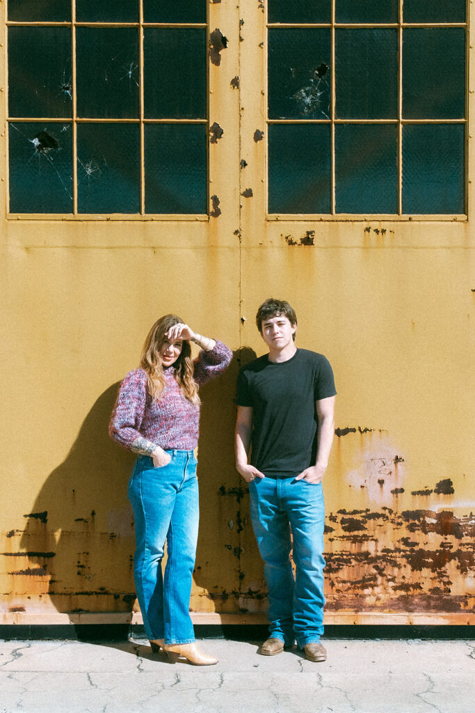 Senior and his mom posing together against a weathered yellow hangar at the former Naval Air Station in Alameda.