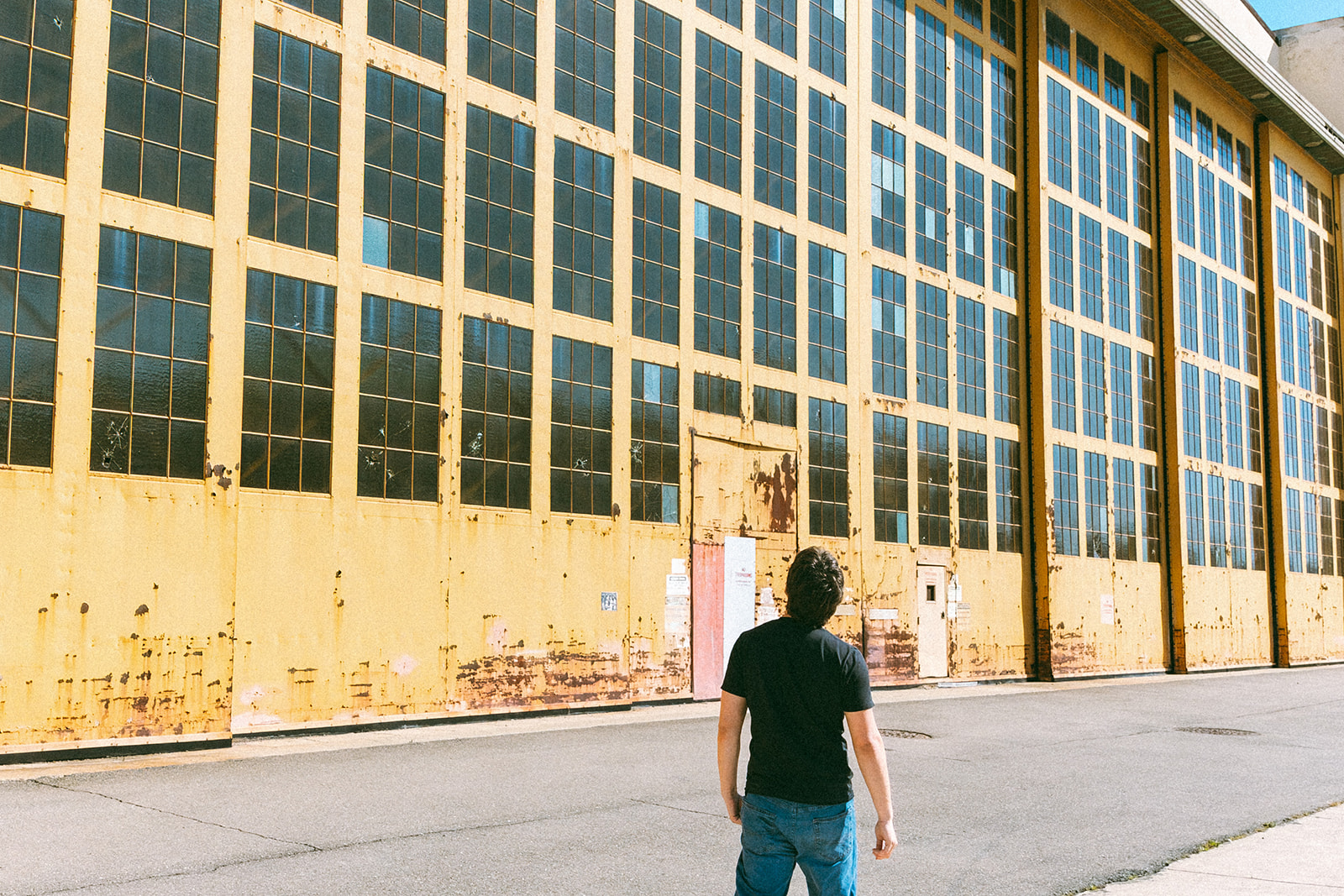 Senior walking toward a large weathered hangar at the former Naval Air Station in Alameda.