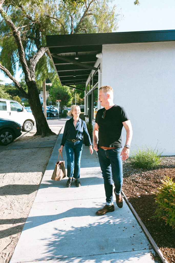 Candid photo of a couple laughing and walking down a sidewalk. 