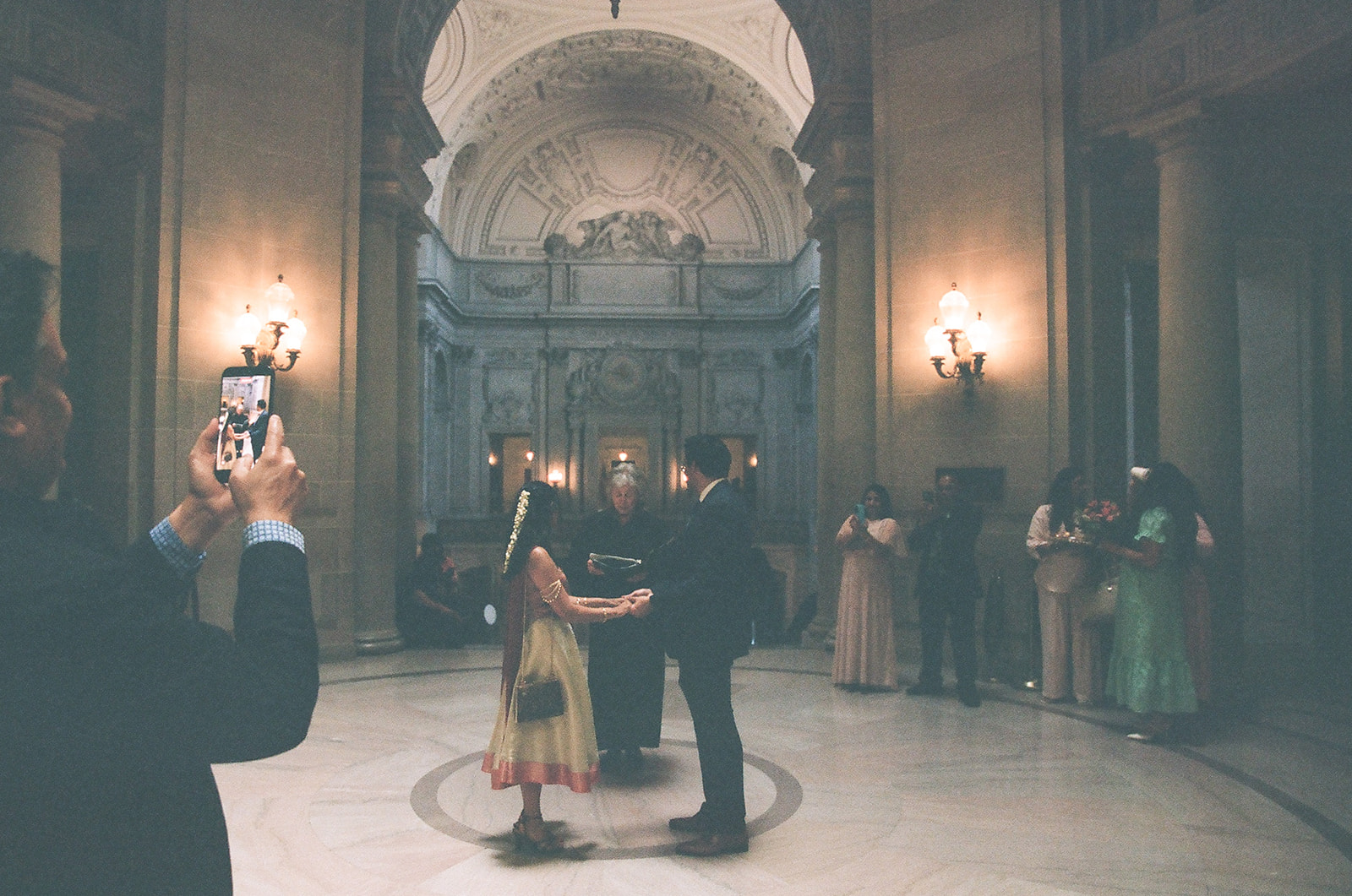 Couple holding hands while their officiant leads their San Francisco City Hall civil ceremony.