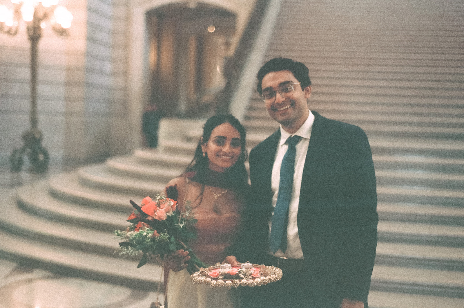 Bride and groom posing together on film near the grand staircase.