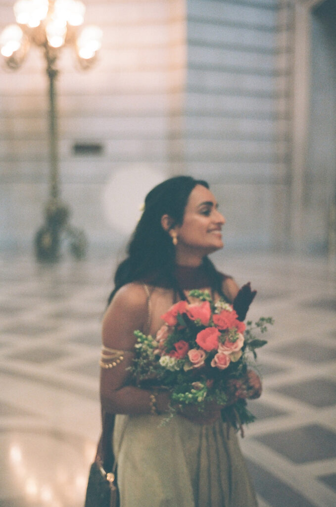 Bride holding a colorful bouquet in a dreamy film portrait inside San Francisco City Hall.
