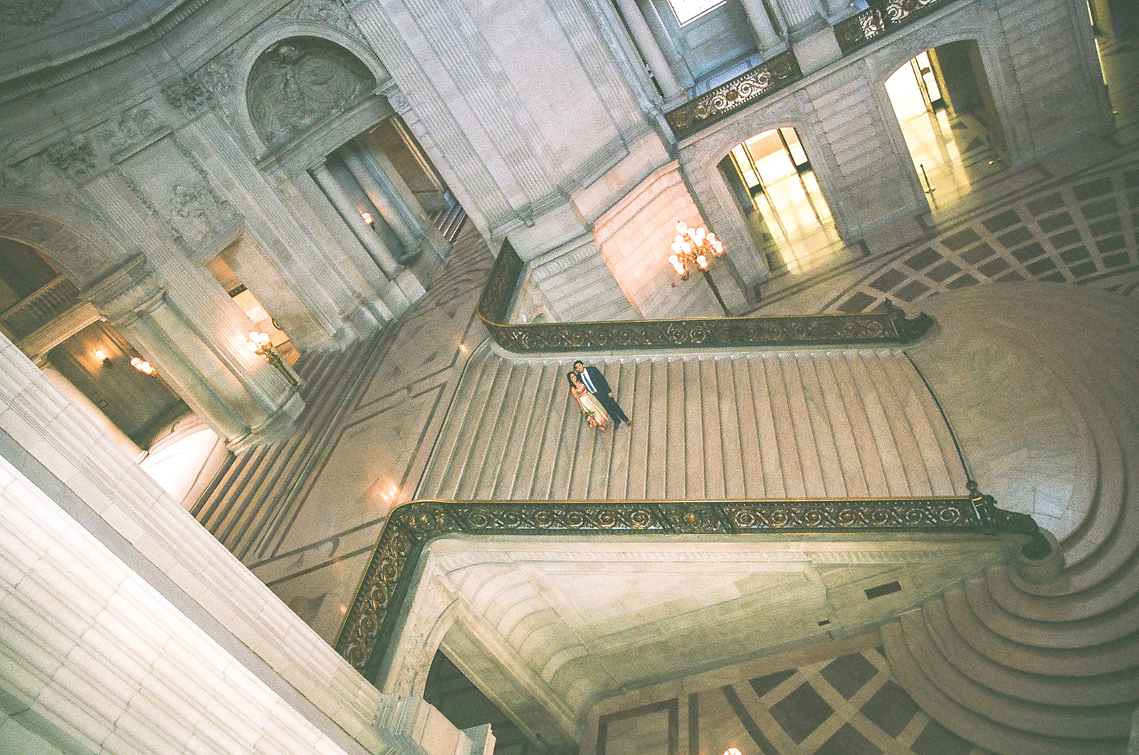 Bride and groom posing on the grand staircase on film.