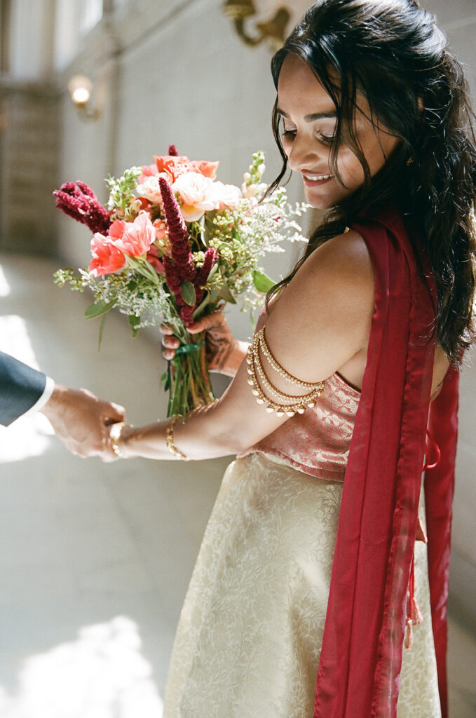 Bride holding her colorful wedding bouquet in the sunlight inside San Francisco City Hall.