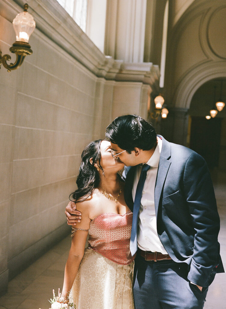 Newlyweds kissing in the sunlight during their San Francisco City Hall wedding photos.