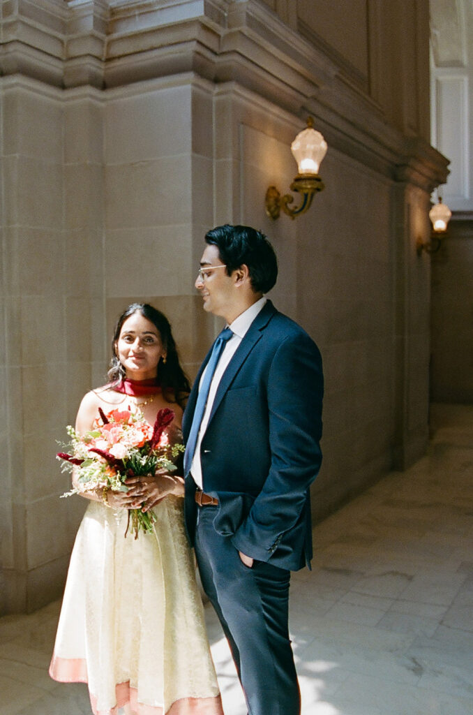 Bride and groom posing inside San Francisco City Hall.