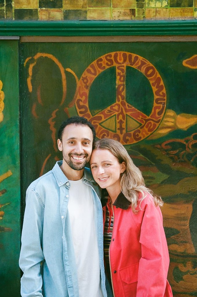 Couple posing in front of wall art graffiti in North Beach. 
