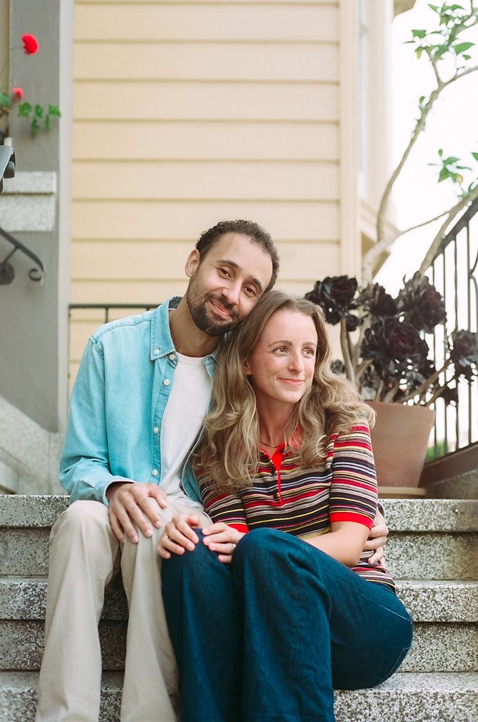Couple sitting on their porch stoop in North Beach for their SF engagement photos.
