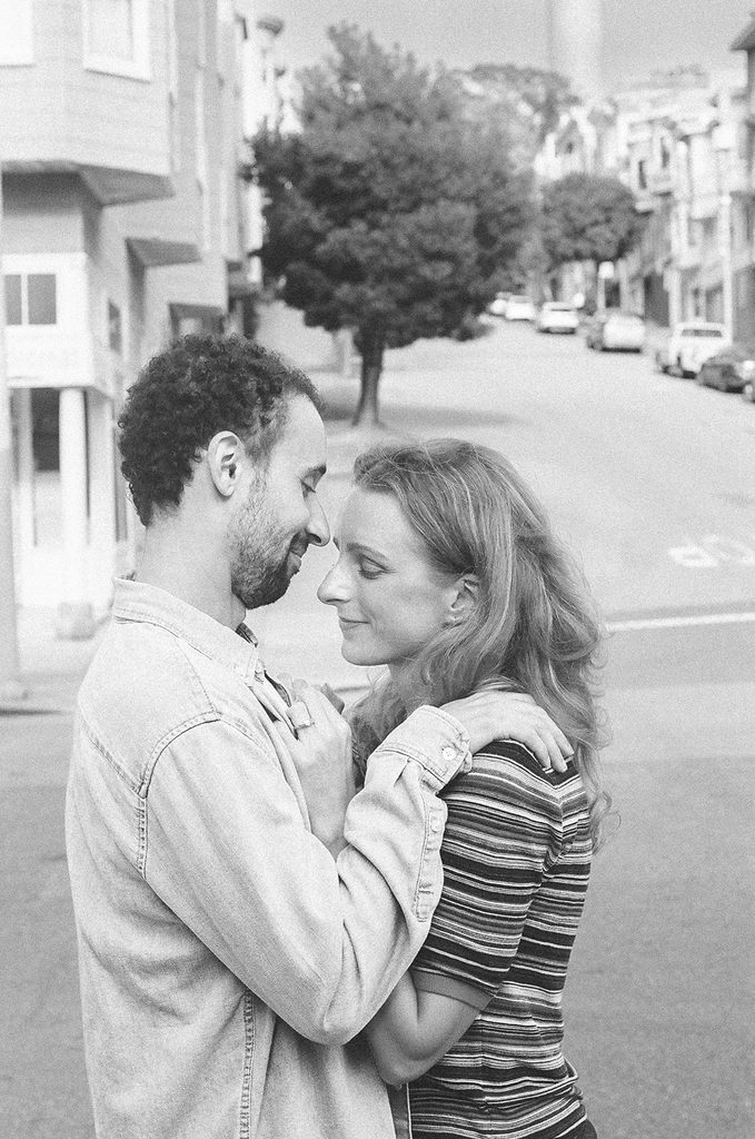 Couple hugging one another in North Beach during their SF engqgement photos.