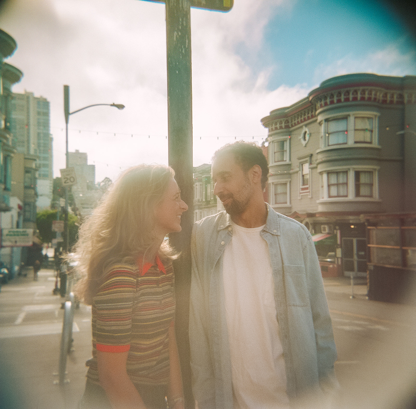 Close-up film portrait of an engaged couple smiling at each other in warm afternoon sunlight.
