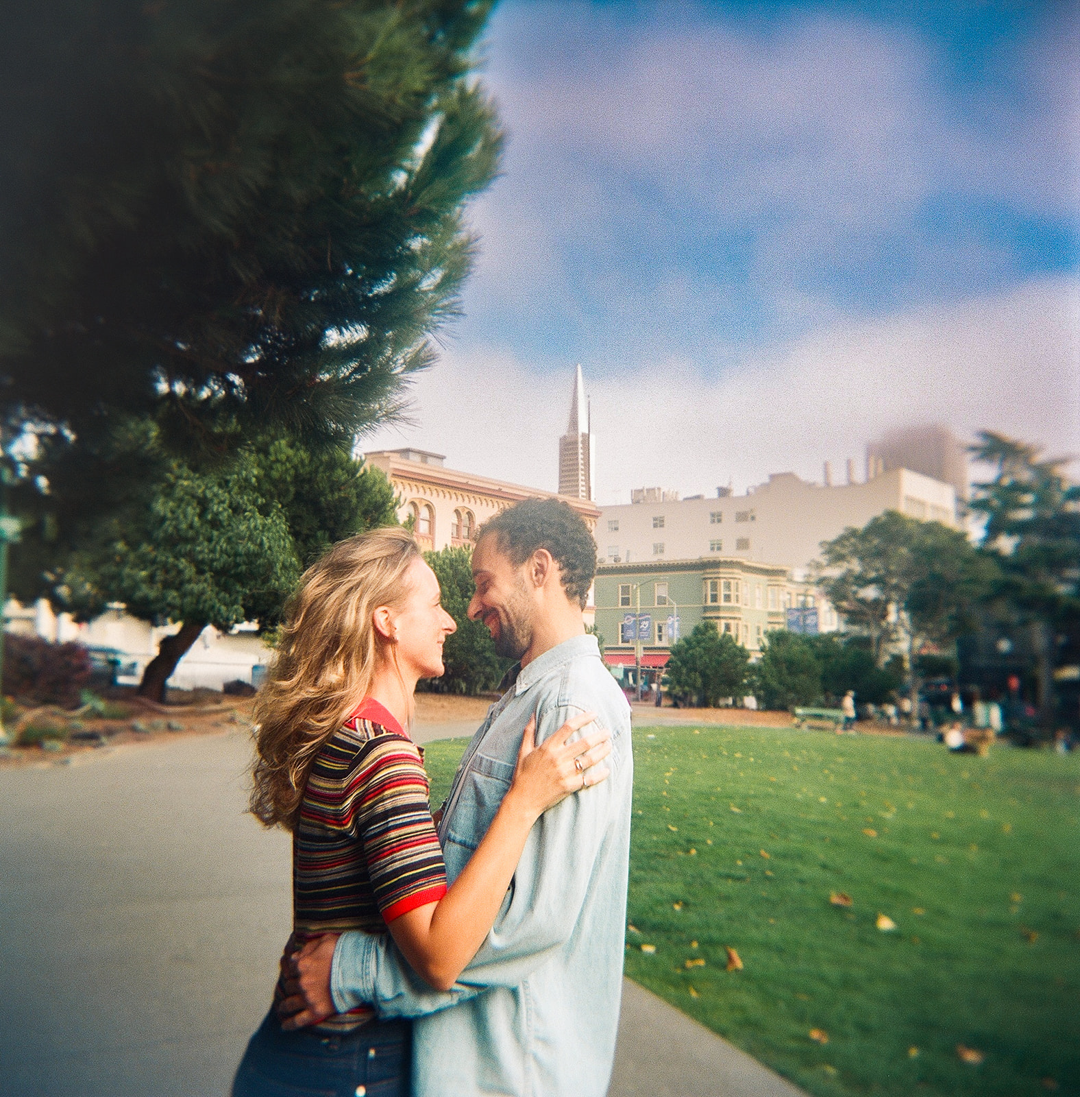 Soft-focus film portrait of a couple holding each other close in Washington Square Park.