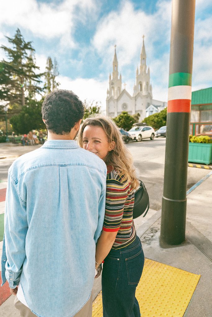 Couple holding hands and waiting to cross the street during their candid SF engagement photos.