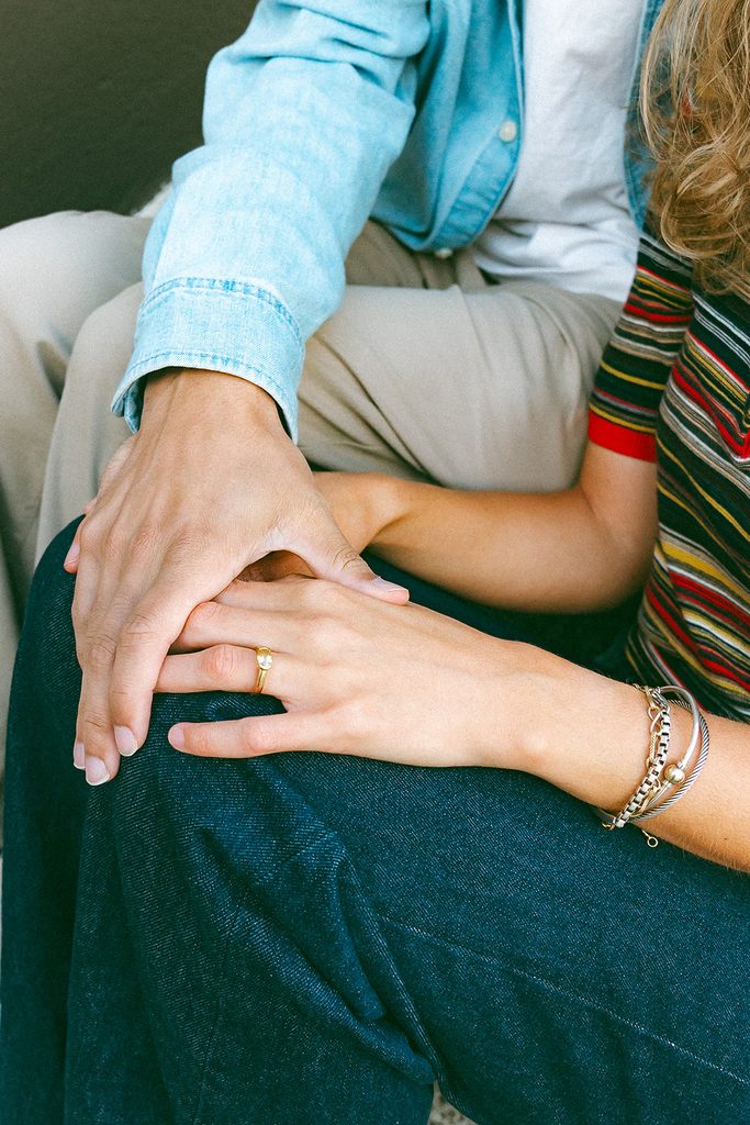 Close up photo of a couple sitting together and holding hands.